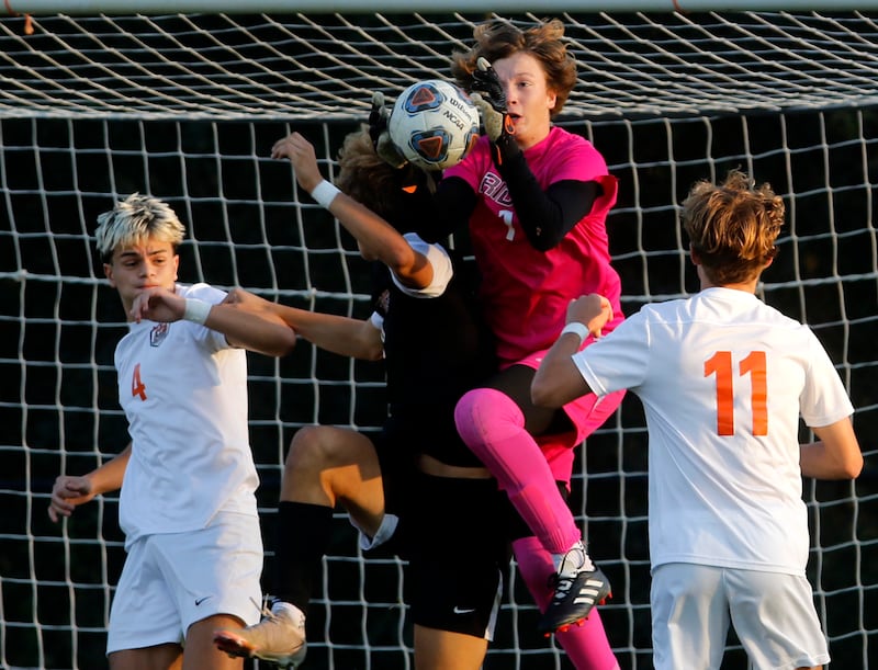 Prairie Ridge's Christopher Zinevich grabs a shot on goal on the shoulder of his teammate, Henry Knoll, between Crystal Lake Central's Alvaro Manzano (left) and Mason McIntyre right during a Fox Valley Conference soccer match on Thursday, Oct. 10, 2024, at Prairie Ridge High School.