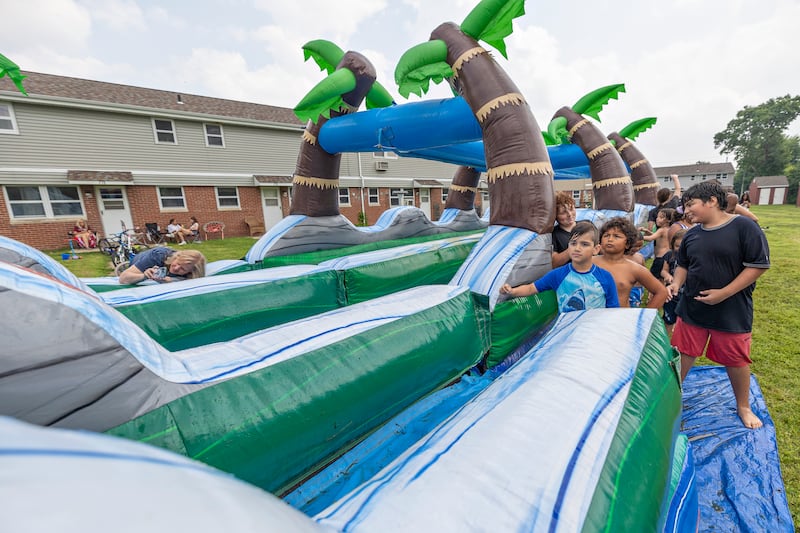 Kids line up Friday, Aug. 1, 2025, for a run down the water slide at the Coloma Township Homes in Rock Falls. The day after a cookout, the housing authority set up the water slide for the day of fun.