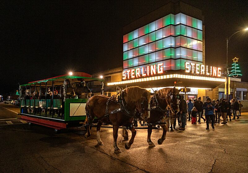 A horse drawn carriage moves past the Sterling theater Friday, Dec. 1, 2023 as revelers take a ride through the downtown for the Seasonal Sights and Sounds Christmas walk.