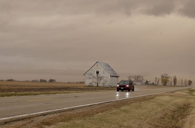 A view of a sepia colored sky next to a barn on Route 251 on  Wednesday, March 19, 2025, in Peru. "Dirty rain" caused by wind and smoke from the West.