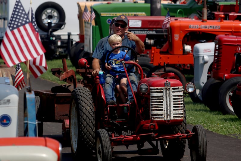 Dennis Storlie of McHenry waits with grandson Wylee, 2, before parking his mid-Fifties International Cub Lowboy  at the McHenry County Fair in Woodstock on Tuesday. Storlie said the tractor was originally purchased by his grandfather.