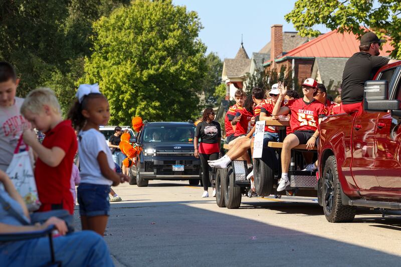 St. Anne High School football players wave to attendees as they ride a float in the Grand Pumpkin Parade during the St. Anne Pumpkin Festival on Saturday, Oct. 4, 2025.