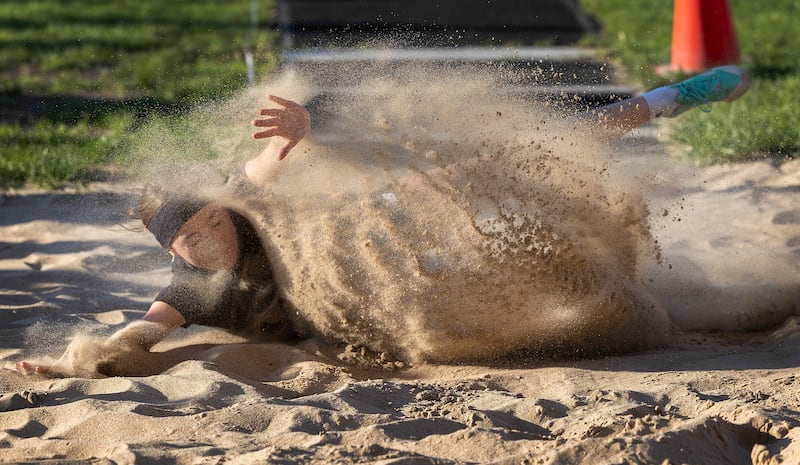 Rock Falls’ Maya Kobbeman splashes down in the long jump pit Thursday, May 8, 2025, during the girls Big Northern Conference track meet. (I love how you can clearly see her face and that hand coming from the sand. The backlighting made this that much more beautiful.)