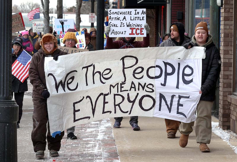 Protesters chant and carry signs as they march west down the sidewalk on Lincoln Highway in DeKalb Tuesday, Jan. 20, 2026, as part of a larger national Free America Walkout. The group is protesting what they perceive as an escalating fascist threat under President Donald Trump and his administration.