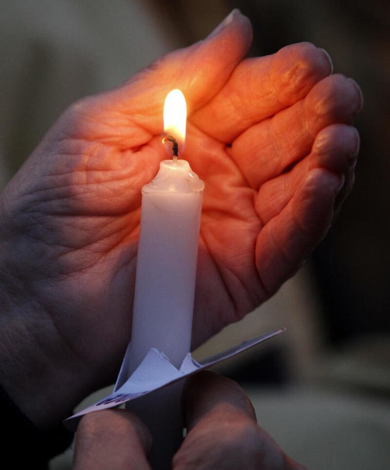 Norma Karsten of Marengo holds a lit candle during a vigil for domestic violence victims put on by Turning Point on Wednesday, Oct. 7, 2015, at Woodstock Square in Woodstock.