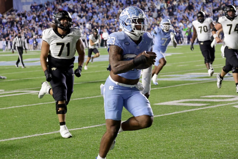 North Carolina linebacker Power Echols (23) runs an interception past Wake Forest offensive lineman Keagen Trost (71) en route to a touchdown during the second half of an NCAA college football game Saturday, Nov. 16, 2024, in Chapel Hill, N.C. (AP Photo/Chris Seward)