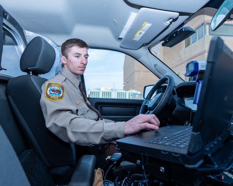 Newly graduated Deputy, Andrew Damron scrolls on Mobile Data Terminal inside LaSalle County Sheriff Truck on Tuesday, December 23, 2025 at LaSalle County Correctional Sheriffs Office in Ottawa. Deputy Damron is one of the 6 newly hired to the agency this December.
