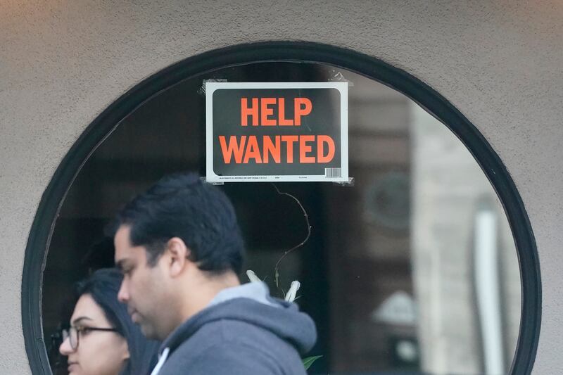 FILE - Pedestrians walk past a help wanted sign posted on the door of a restaurant in San Francisco, Tuesday, April 18, 2023. (AP Photo/Jeff Chiu, File)
