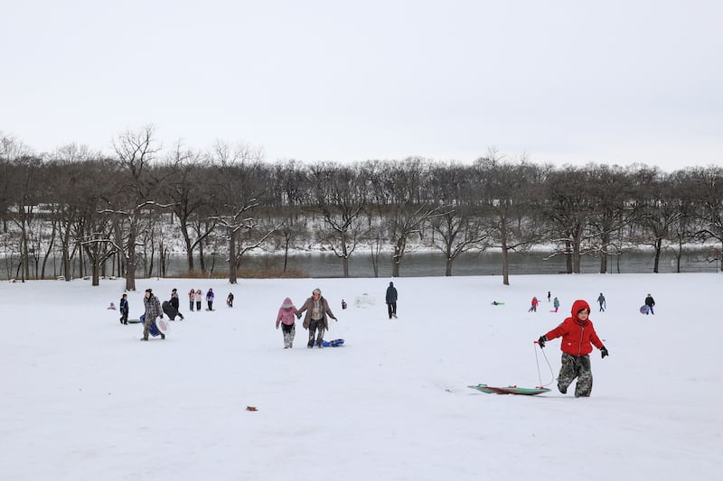Sledders trek back up the hill at Helgeson Park in Bradley on Sunday, Nov. 30, 2025.