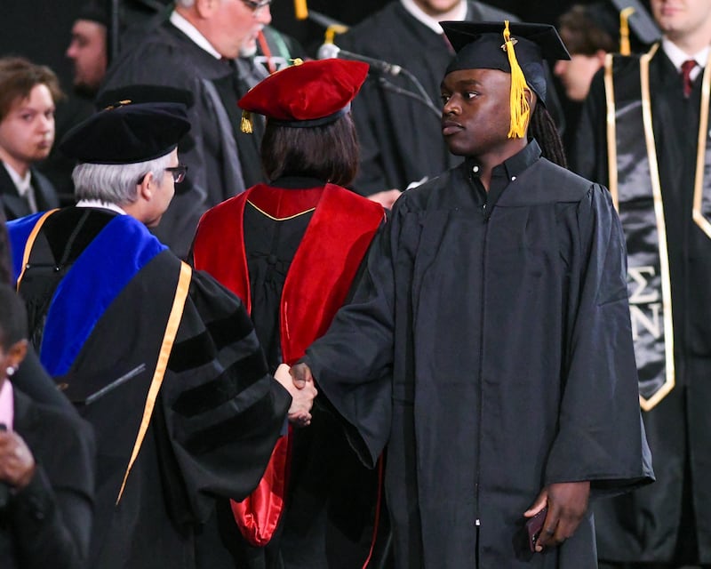 A Northern Illinois University graduate receives his diploma on Saturday May 10, 2025, during the graduation ceremony held at the Convocation Center in DeKalb.