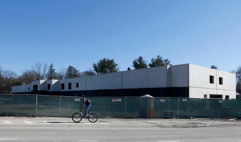 A person rides their bicycle past a partially constructed five-story, 100-unit apartment complex at 401 Algonquin Road near Route 14 in Fox River Grove on Tuesday, March 16, 2023. Contractors allege in court records that they haven't been paid for work on the building, which had drawn the ire of neighbors and concerns from the Fox River Grove Fire Protection District.