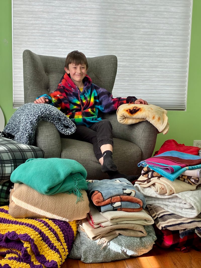 Aaden Barcus, 9, of Crystal Lake, sits surrounded by about 25 blankets he collected to give to people who are unhoused.