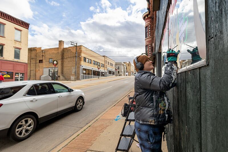 Nora Reuter works on a window painting Wednesday, Nov. 20, 2024, in downtown Dixon. Artist Reuter plans the decorate eight local businesses and organizations.