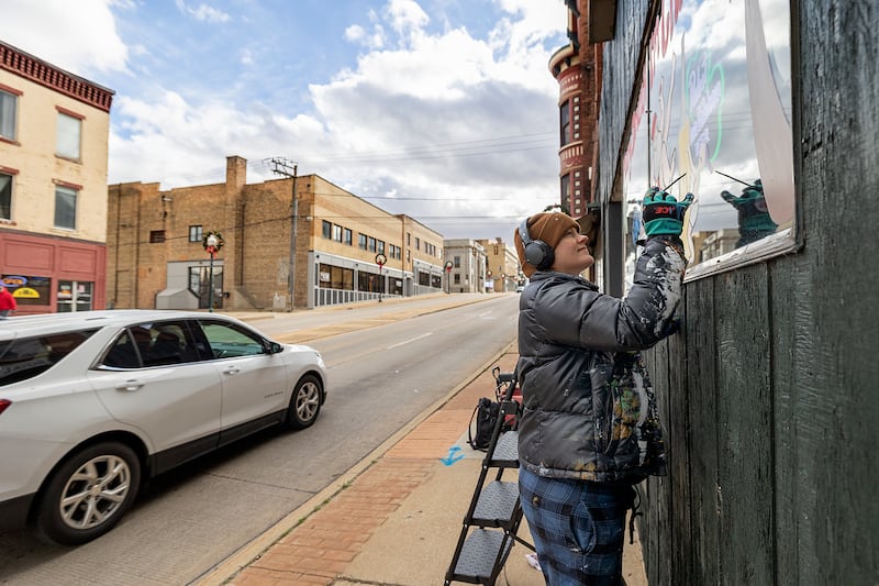 Nora Reuter works on a window painting Wednesday, Nov. 20, 2024, in downtown Dixon. Artist Reuter plans the decorate eight local businesses and organizations.
