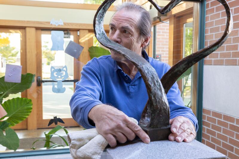 Artist Mike McNamara checks the positioning of his work Monday, Oct. 20, 2025, in Franklin Grove. A sculpture dedicated to Winifred Knox is being put into place at the library.
