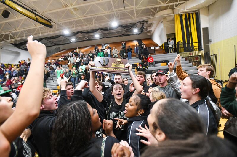 Bishop McNamara's Trinity Davis hoists the IHSA Class 2A Herscher Sectional championship plaque as the student fan section joins the team to celebrate on the court following the Fightin' Irish's 69-38 victory over Watseka-Milford on Thursday, Feb. 27.