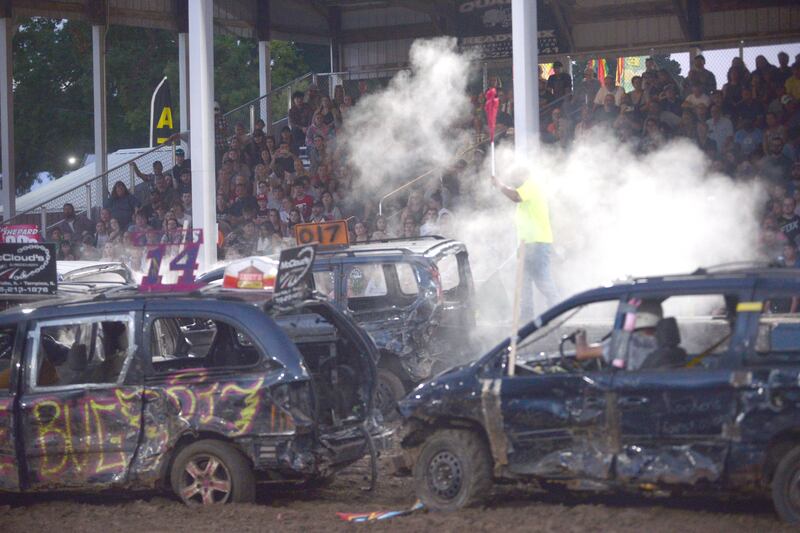A track official pauses the action in the mini van/SUV heat at the Whiteside County Fair's demolition derby on Saturday, Aug. 17, 2024.