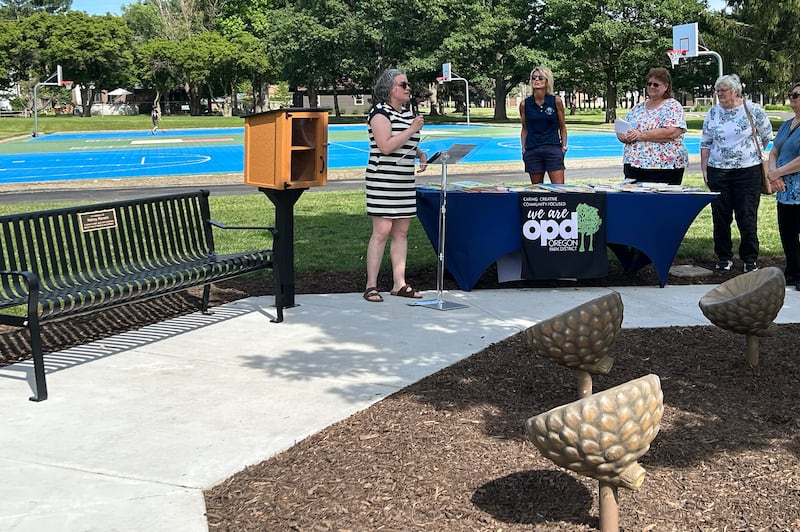 Colleen Berg, the daughter of the late Nancy Kerwin, speaks to the crowd during the Thursday, May 28, 2026, dedication of a free Little Library, commemorative bench, and children’s seating area in memory of her mom at Oregon Park West.