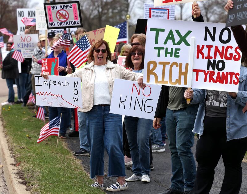 Protesters demonstrate along Sycamore Road in front of Hopkins Park Saturday, April 19, 2025, during a “No Kings” rally and march in DeKalb. The group was protesting what they’ve argued is the unlawful and harmful federal policies of President Donald Trump and his administration.