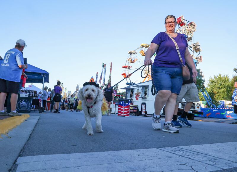Michele Sharpe, of Manteno, walks her goldendoodle Molly, dressed in a sequined tutu and hat, down Main Street in the South Creek Animal Hospital Pet Parade during Manteno's Oktoberfest on Friday, Sept. 26, 2025.