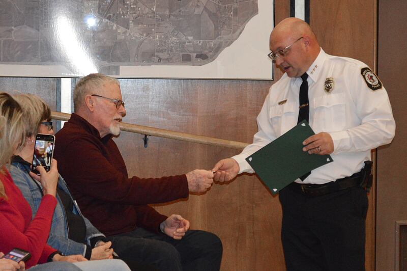 FILE: Rock Falls Police Chief David Pilgrim hands Tim Isaac, of Rockford, a challenge coin during the March 19, 2024, Rock Falls City Council meeting. Pilgrim and others were honored at the meeting for saving Isaac's life Feb. 14, 2024, after Isaac had a medical emergency while driving.