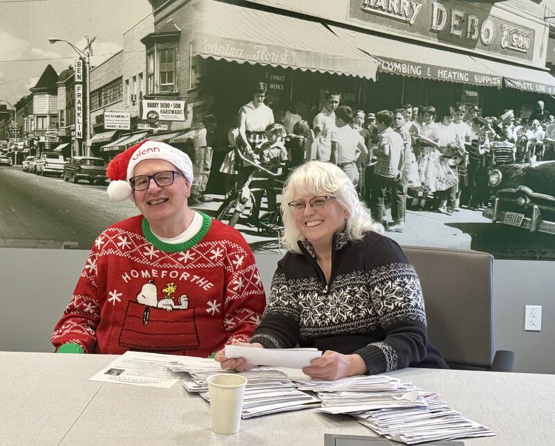Tree of Hope Chairperson Glen Underwood and Horizon House CEO Michelle Rich open donation letters for the 2025 Tree of Hope campaign in the Michael G. Debo meeting room.