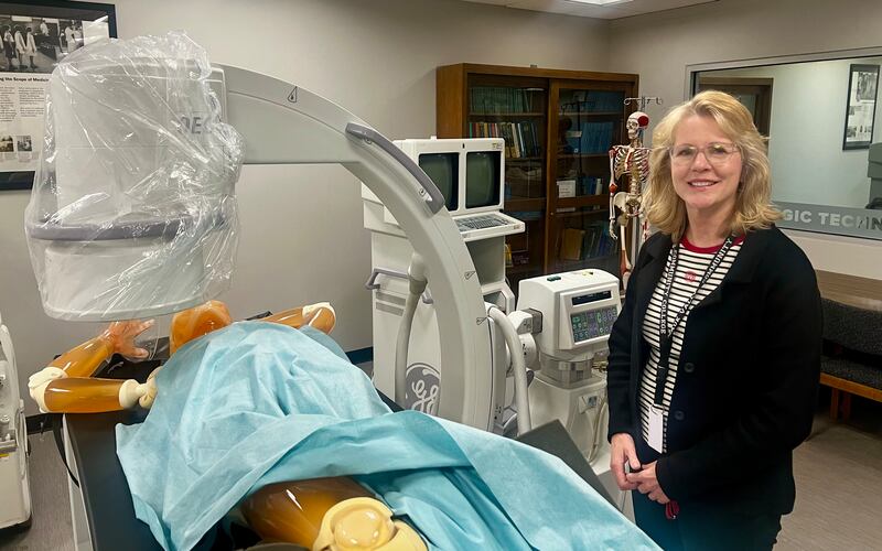 Sauk Valley Community College's Radiology Program Director Dianna Brevitt stands beside an x-ray machine and simulation dummy.