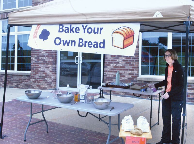Volunteer Julie Tucker helps at the "Bake Your Own Bread" booth by the Windmill Cultural Center in Fulton during the 25th anniversary celebration in Fulton on June 7, Two more baking dates have been set where people can purchase a bag of stone ground flour - from the de Immeigrant Windmill -  mix it up,  knead it into dough and drop in the oven at the Windmill Cultural Center, from 10 a.m. to 2 p.m. on Saturday, July 5 and Saturday, Aug. 2.