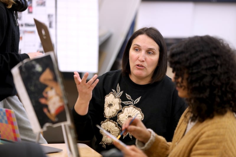 Stephanie Dodd, an art teacher and soccer coach at St. Charles North High School, works with student Simone Wright in her advanced placement art class.