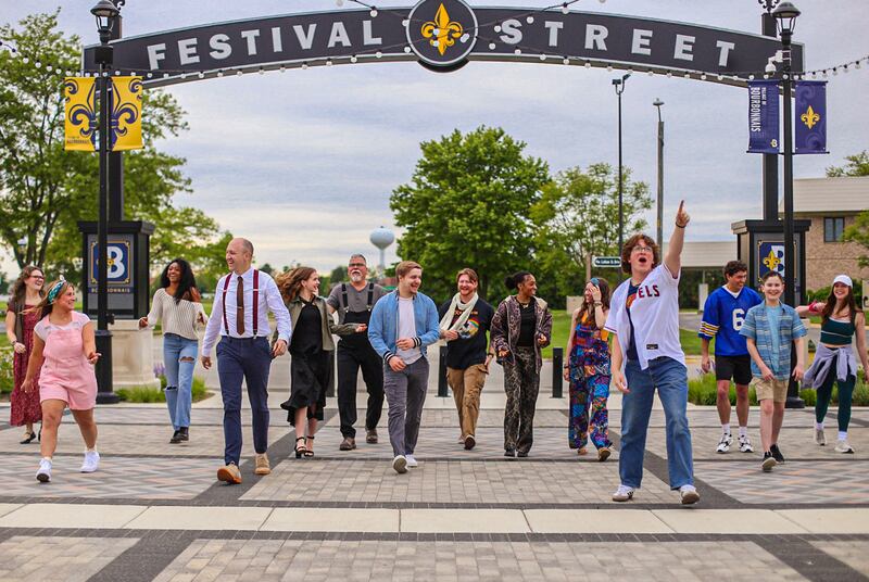 The cast of Acting Out Theatre Co.’s “Godspell” walk along Festival Street at The Grove in Bourbonnais, where performances will take place July 18-20.