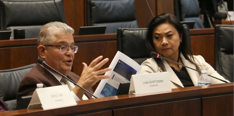 Illinois Accountability Commission Chair Judge Ruben Castillo holds up a copy of the commission’s initial report at its second public hearing in Chicago on Friday.
