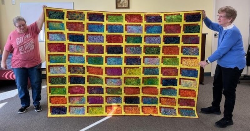 Pictured are club members Nickie Lingbeck and Karna Croft displaying the quilt, called “Illusion.”