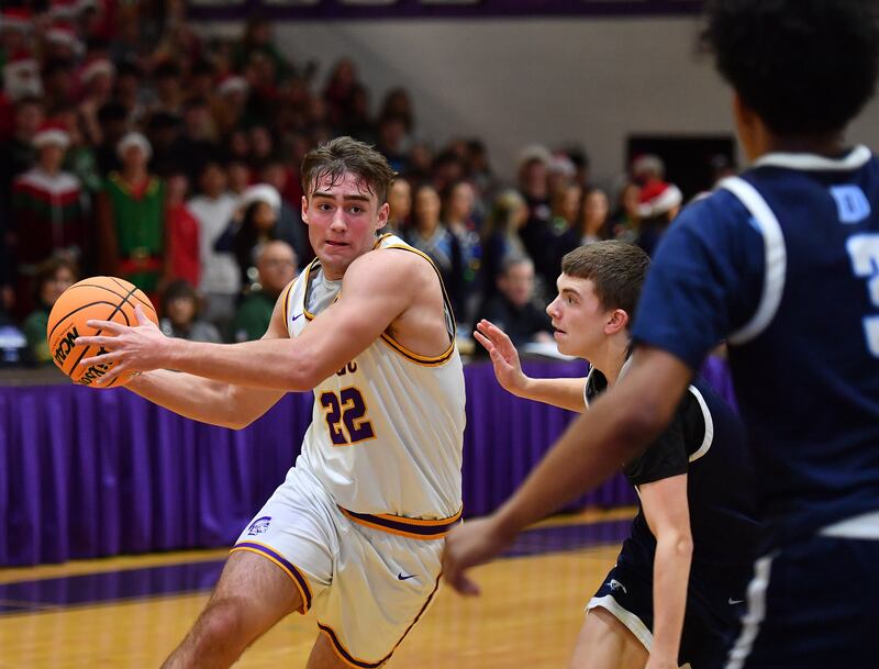 Downers Grove North’s Jacob Vroman (22) drives to the basket against two Downers Grove South defenders during a game on December 20, 2025 at Downers Grove North High School in Downers Grove.