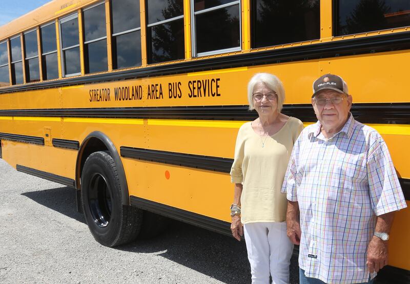 Authur and Linda Simpson pose for a photo next to a school bus on Monday, July 28, 2025 at the Streator-Woodland Bus Company. The Simpsons have a combined 101-years of driving a school bus.