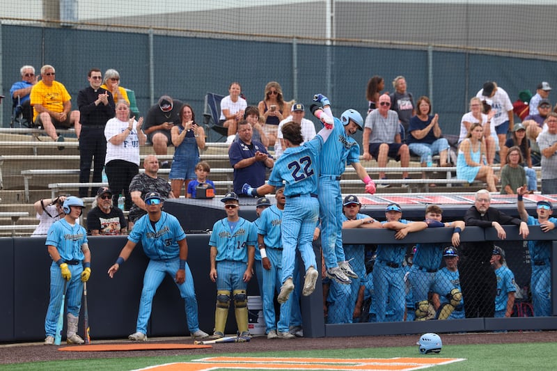Marquette's Griffin Dobberstein (22) leaps with teammate Easton DeBernardi in celebration of a two-run homer during the Crusaders' 4-1 victory over Freeburg in the IHSA Class 2A third-place game Saturday, June 13, 2026, at the University of Illinois in Champaign.