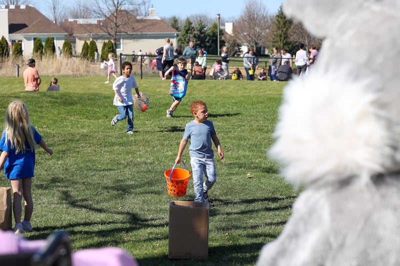 Children run to collect plastic eggs as the Easter bunny looks on during the Riverside Senior Life Easter Egg Hunt hosted at Westwood Trails Assisted Living in Kankakee on Saturday, March 21, 2026.