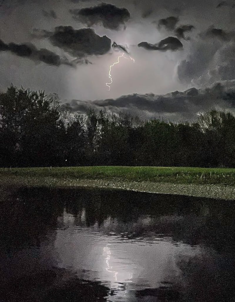 A lightning strike is reflected in a pond across from Walmart.