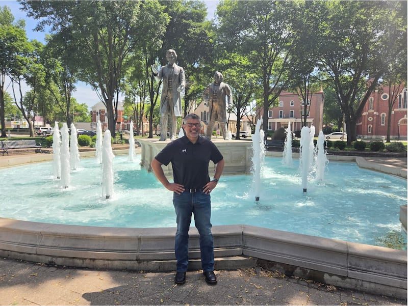 Lieutenant Governor candidate Aaron Del Mar on Thursday, June 4, 2026, at Washington Park in Ottawa, standing in front of the statue commemorating the Lincoln-Douglas debate.