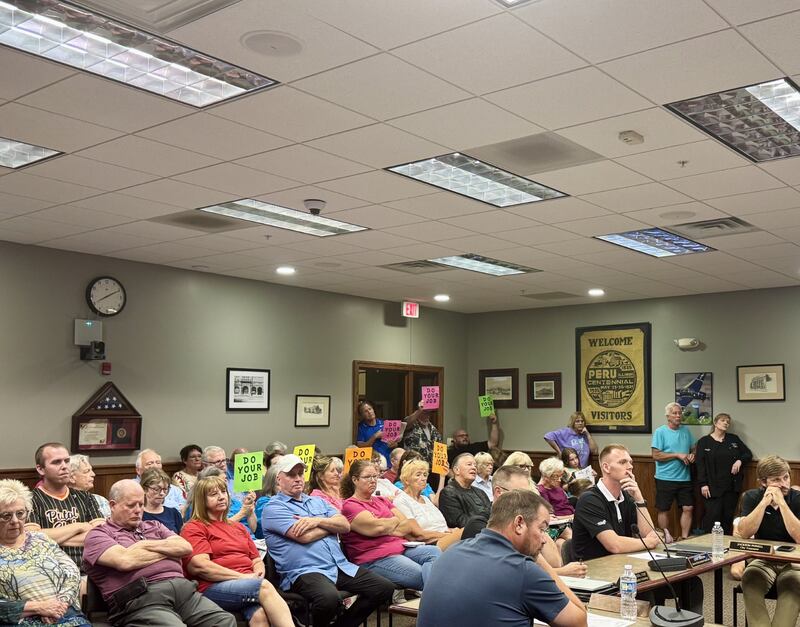 Peru residents hold up signs saying "Do your job" during Monday night's council meeting.