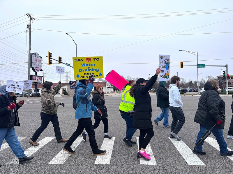 Protestors against a Joliet data center march through an intersection Saturday, March 14, 2026, in Joliet.