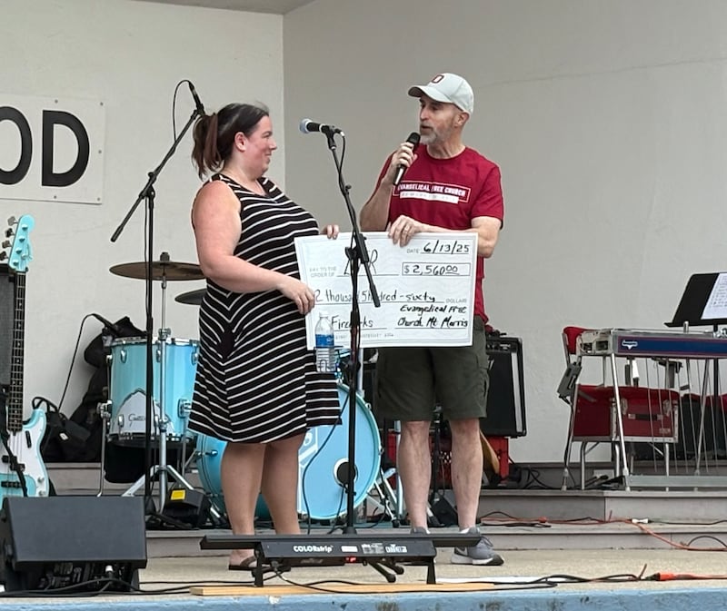 Bruce McKanna, pastor of the Evangelical Free Church of Mt. Morris, presents a check to Let Freedom Ring Committee Chairman Catherine Higley at the June 13 Jamboree. The final amount of the donation was $2,871, 100 percent of the donations received at the church's food concession that evening.