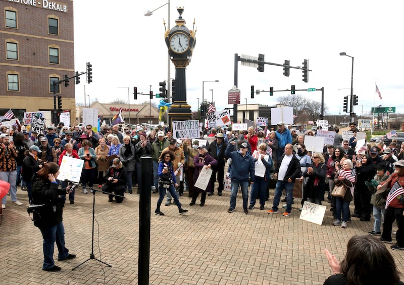 Hundreds of people listen to speakers Saturday, April 5, 2025, during a Hands Off! rally at Memorial Park on the corner of First Street and Lincoln Highway in DeKalb. The group gathered to protest against various policies of President Donald Trump and his administration.