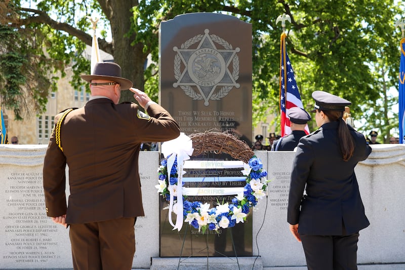 Officers salute after placing the wreath at the memorial wall during the Kankakee County Law Enforcement Memorial on Thursday, May 14, 2026, at the Kankakee County Courthouse.