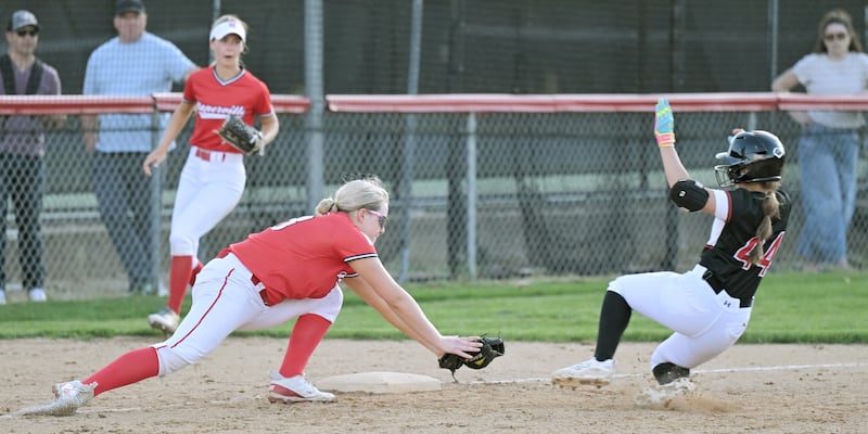 Naperville Central third baseman Lyla Hope reaches to tag out Benet Academy baserunner Sofia Heggie as she tries to advance on a fly ball to right field in a softball game in Lisle on Thursday, Apr. 16, 2026. the catch and throw was made by right fielder Fiona Brown.