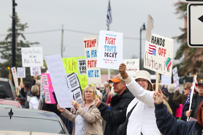 Chris Rorem, right, of Bourbonnais, holds a sign alongside over 250 fellow protesters during the Hands Off Rally at the Kankakee County Courthouse on Saturday, April 19, 2025.
