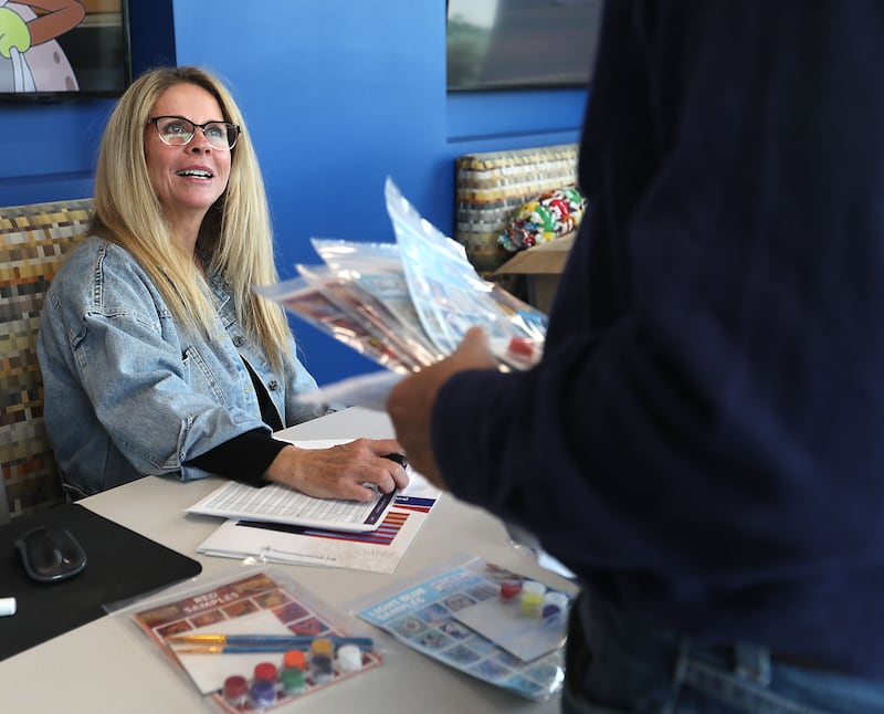 Barb Neises, a  volunteer with the McHenry Riverwalk Foundation, hands out tiles for the McHenry Riverwalk mural project on Thursday, April, 9, 2026, at the McHenry Recreation Center.