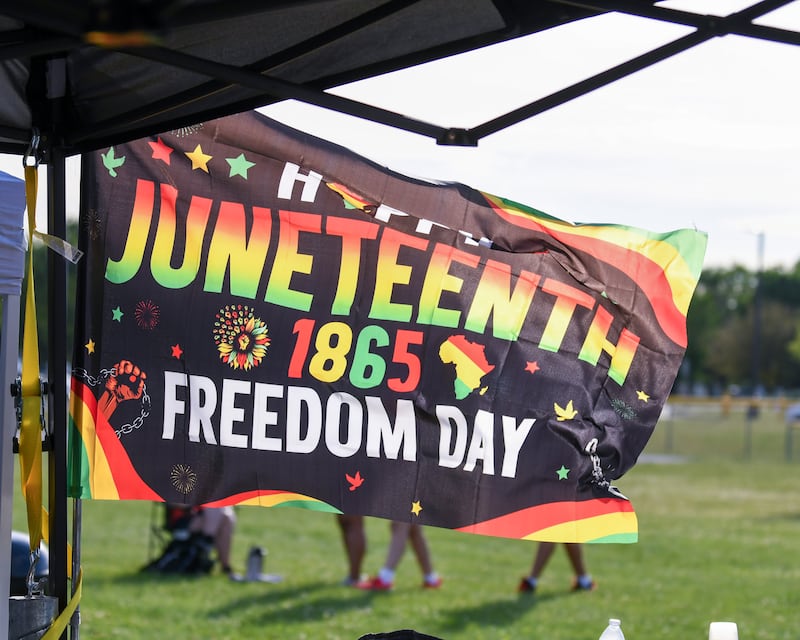 A Happy Juneteenth 1865 Freedom Day flag whips in the wind on Saturday June 15, 2024, during the Juneteenth celebration held at Emily G. Johns School in Plano.