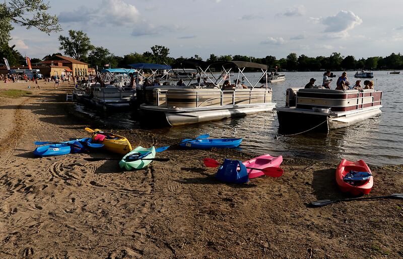 Kayaks and pontoon boats line the beach for Crystal Lake Park District's Concert in the Park on Tuesday, June 17, 2025, at Main Beach in Crystal Lake. The concert was part of the park district's weekly Tuesday night summer concert series.