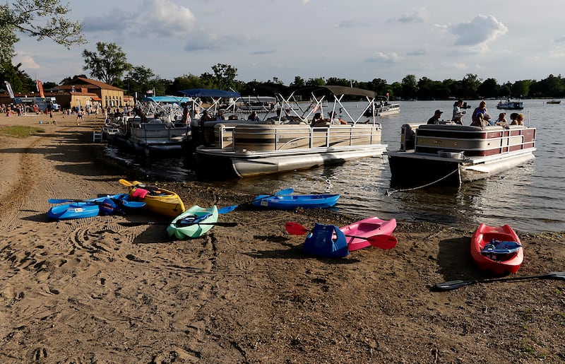 Kayaks and pontoon boats line the beach for Crystal Lake Park District's Concert in the Park on Tuesday, June 17, 2025, at Main Beach in Crystal Lake. The concert was part of the park district's weekly Tuesday night summer concert series.