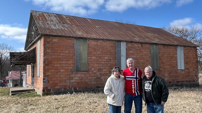 Sue and Chuck Borchsenius stand on each side of Dave Johnson following their donation of the Norway Temperance Hall to the Norsk Museum.